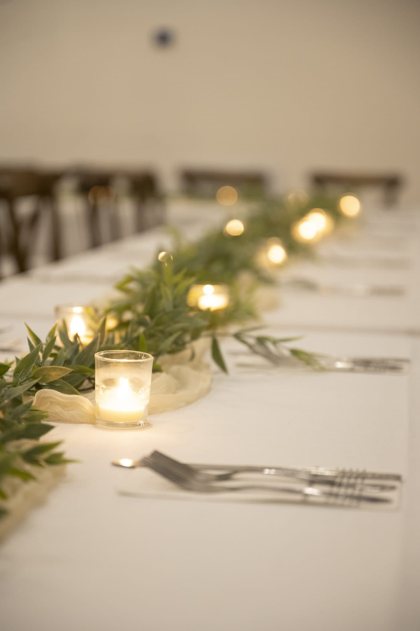 Votive candles and a greenery runner down a long white banquet table at Becker Hill