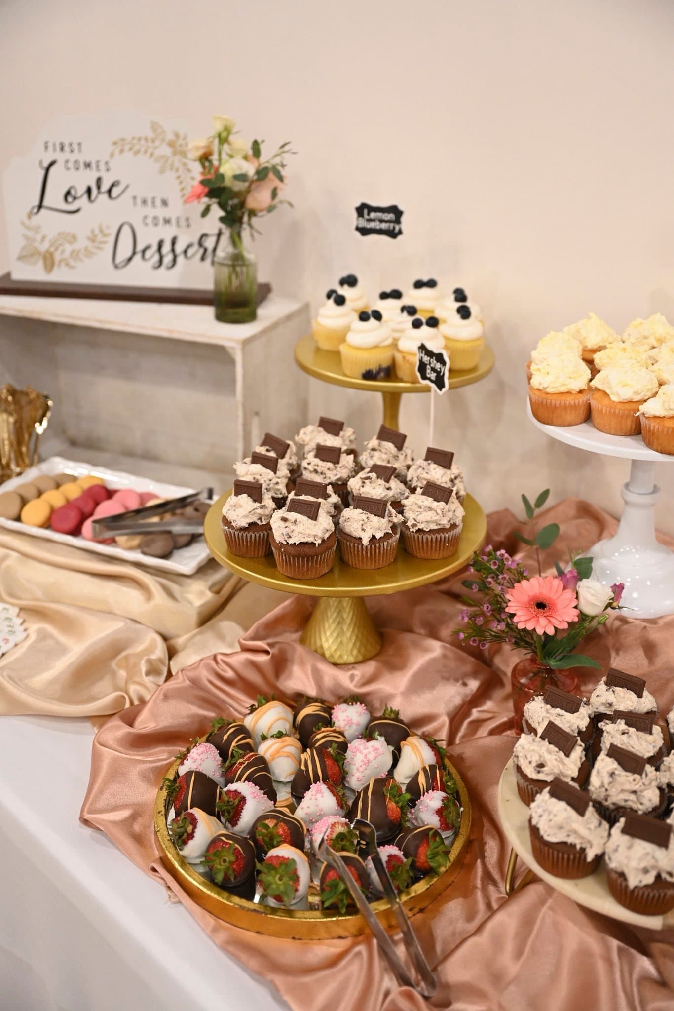 Dessert table with cupcakes, macarons, and chocolate covered strawberries at a Becker Hill reception