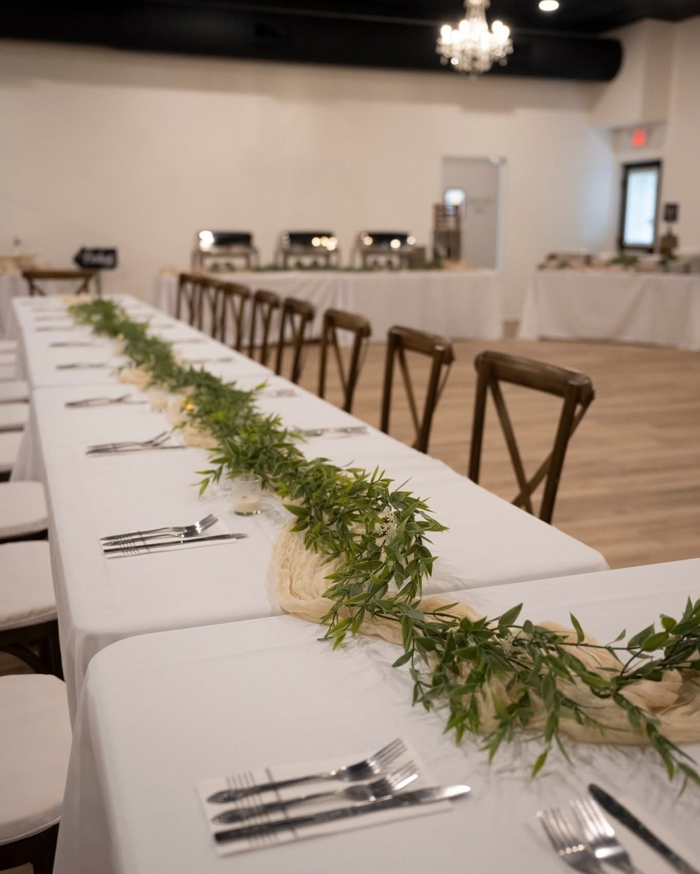 Long banquet table with a fresh greenery runner set for a wedding reception at Becker Hill