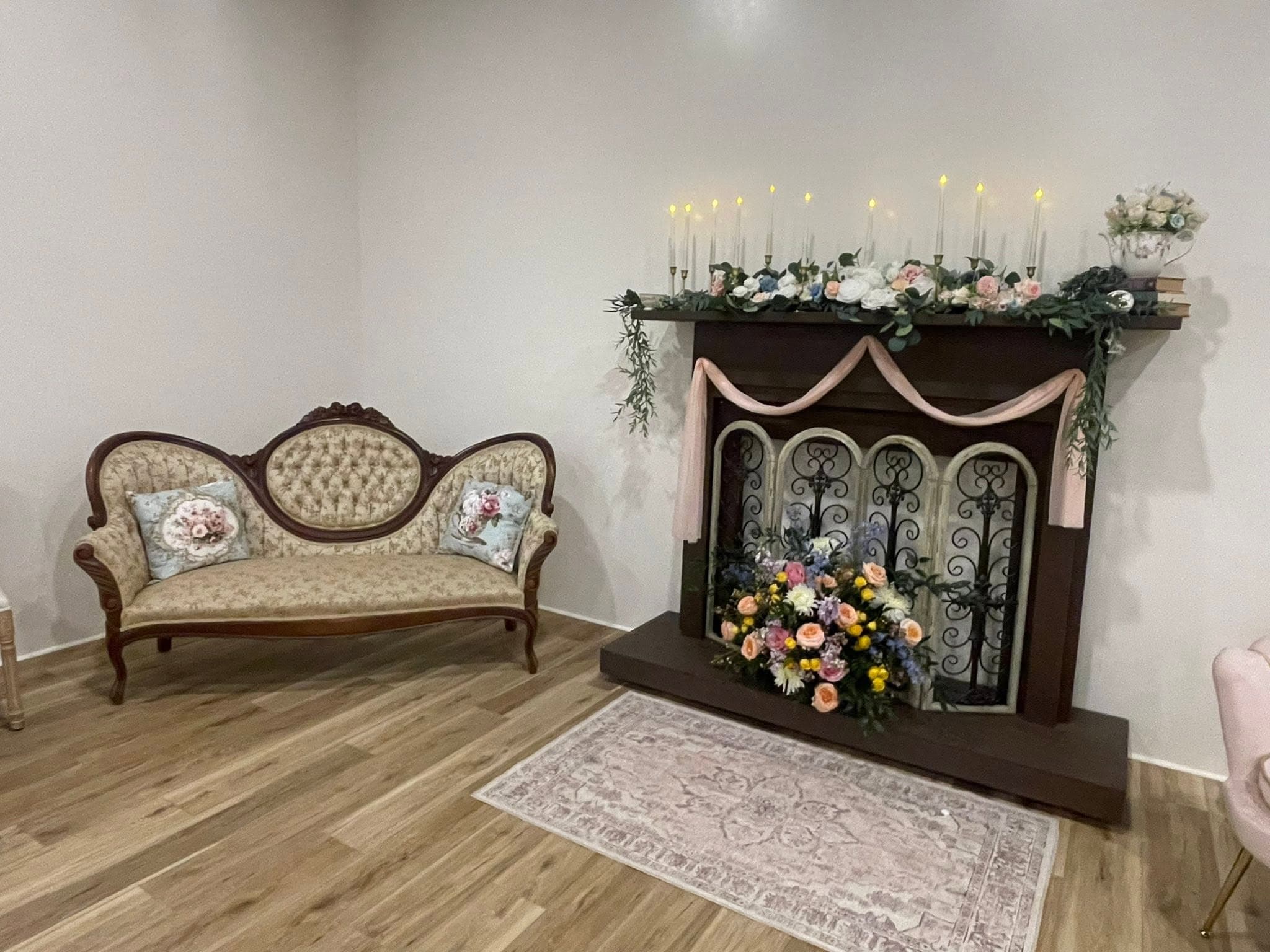 Antique sofa and flower adorned fireplace lounge vignette at Becker Hill