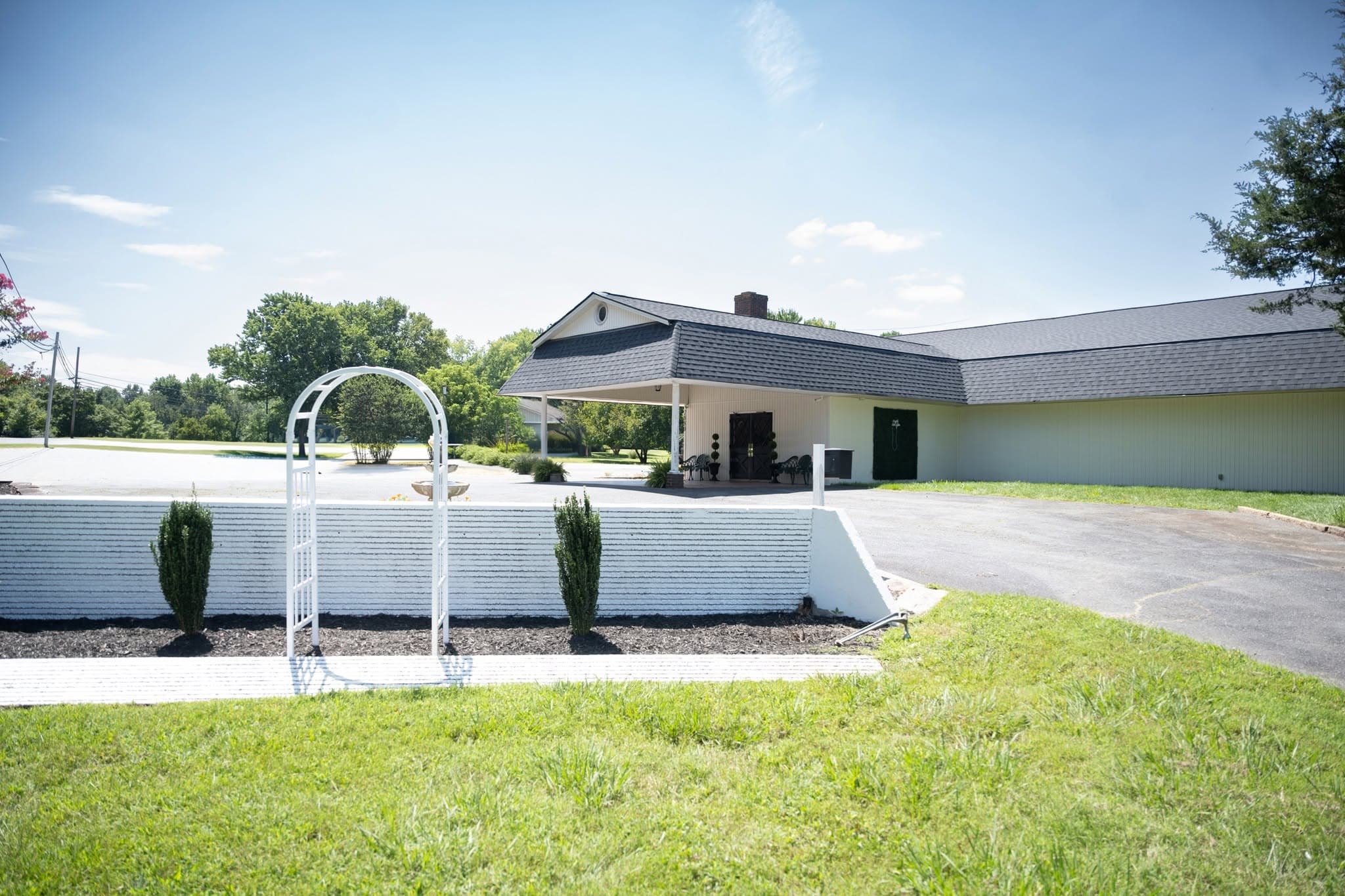 Becker Hill event venue exterior with a white ceremony arch on the lawn in Sophia, NC